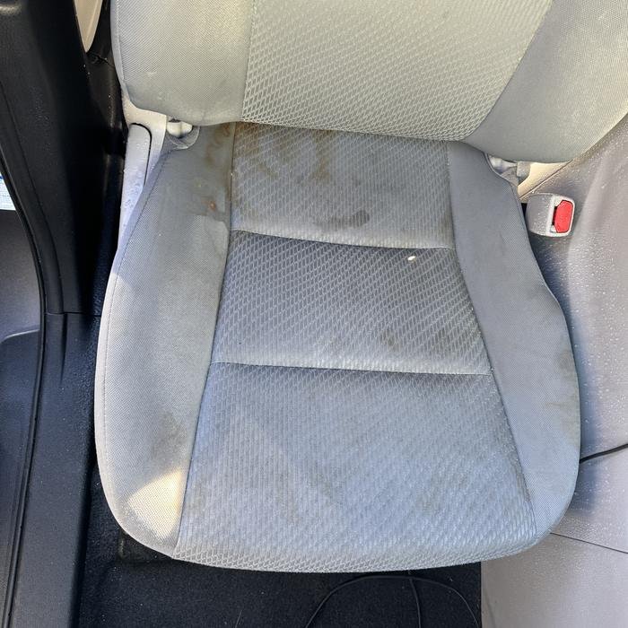 Gray cloth driver seat with dirt stains before shampoo