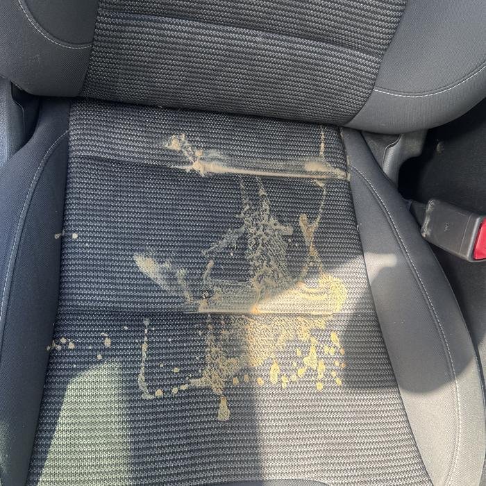 Dark cloth car seat with a dried spill before shampoo