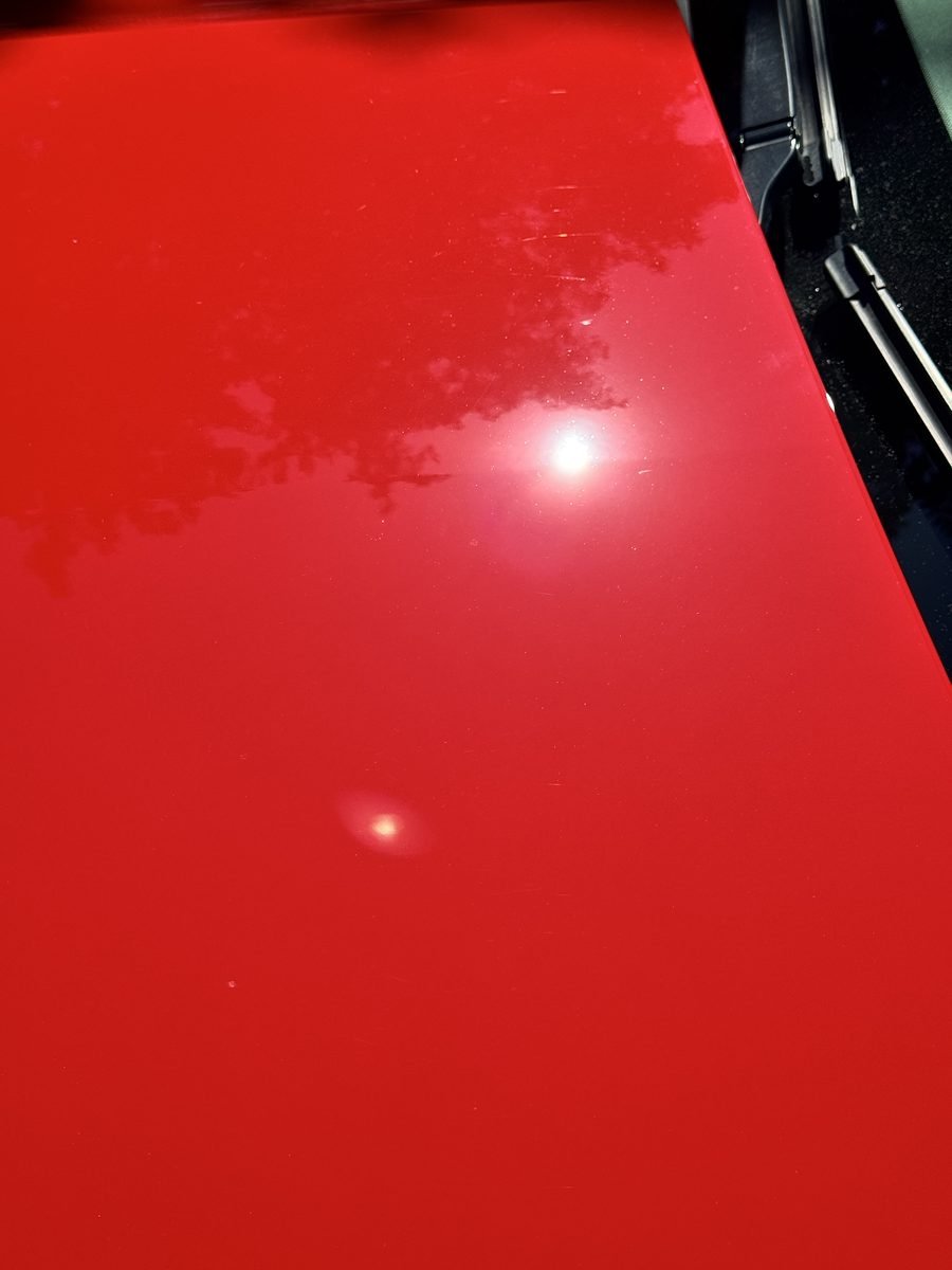 Red Camaro hood after swirl mark removal by machine polishing